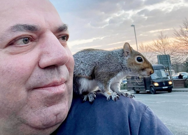 Mehmet Onal with a squirrel that he rescued perched on his shoulder.