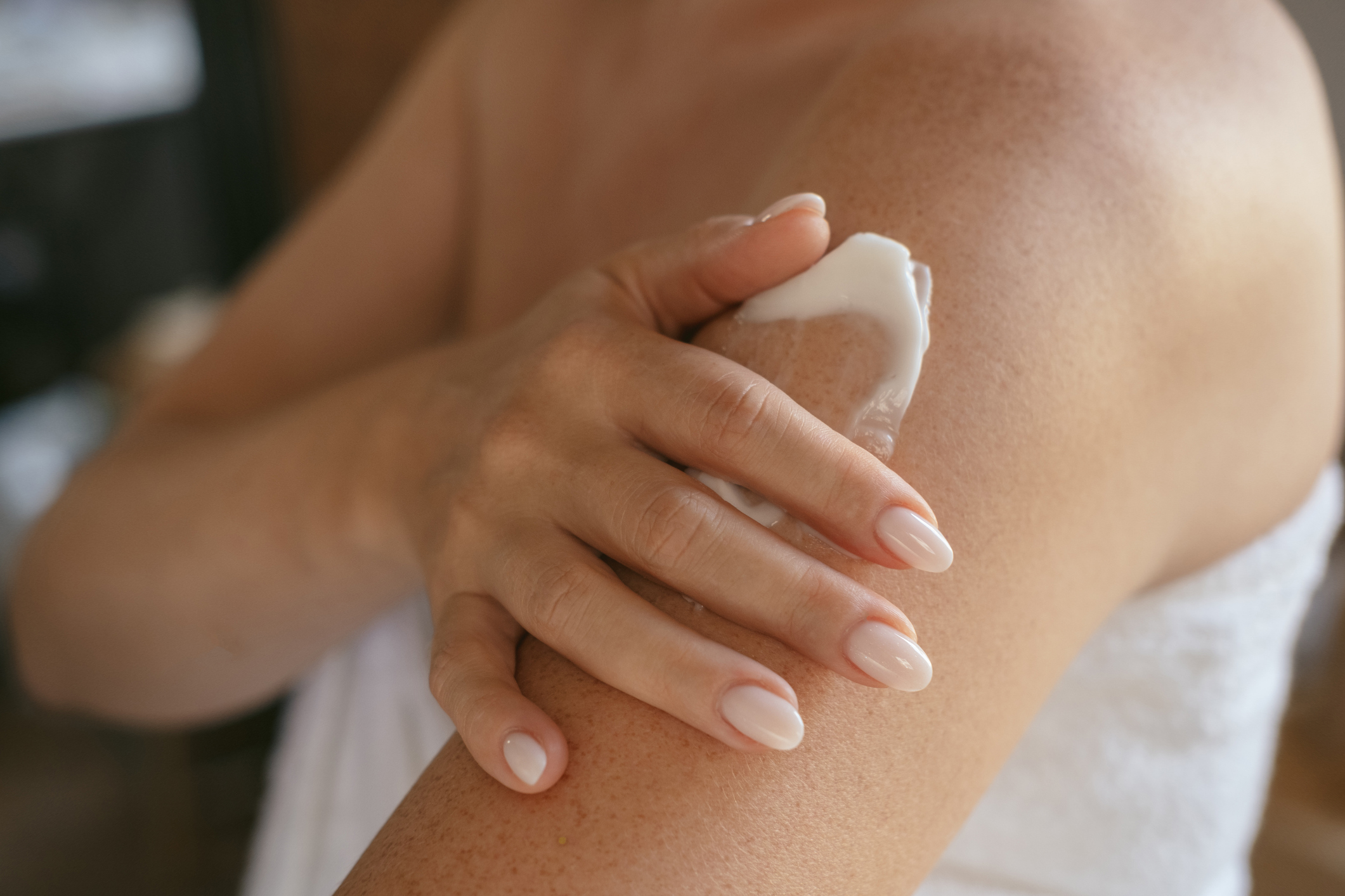 A person applying sunscreen to their arms.